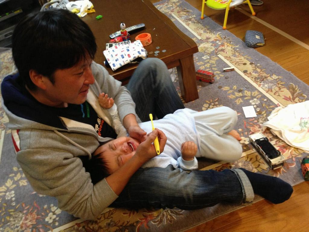 パパがこどもに歯磨きをしている様子